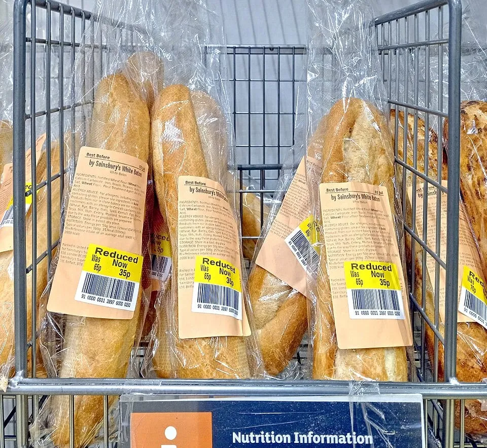 Bagged white batons in a bakery cage, each with a yellow reduced label, marked down from 65p to 35p